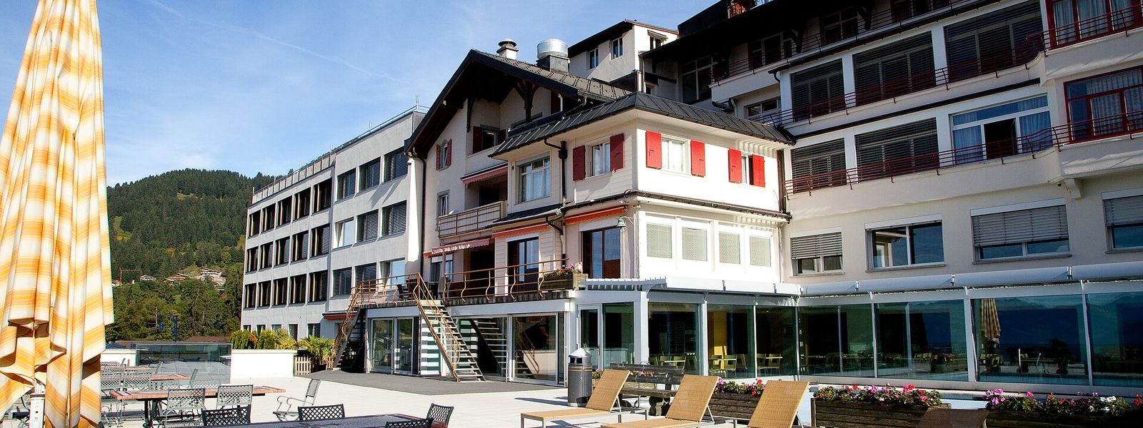 La terrasse et les bâtiments du Collège Alpin Beau Soleil à Villars-sur-Ollon, dont l'aile la plus ancienne aux volets rouges
