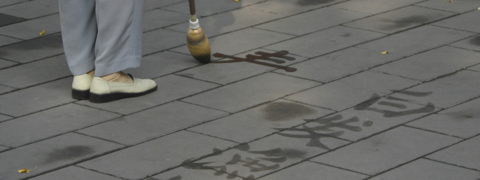 Un homme trace des caractères chinois à l'eau sur les dalles du parc Jingshan, à Pékin