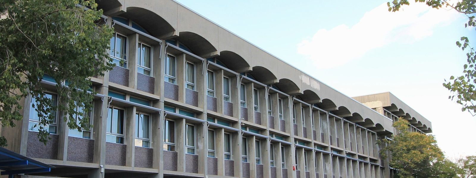 La longue façade en béton à arcades d'un bâtiment du Lycée Français de Madrid, entre deux arbres