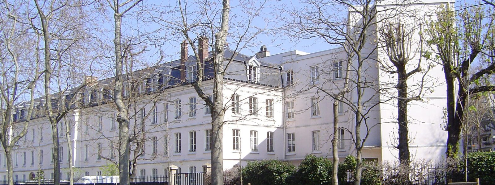 Le bâtiment blanc du collège Sainte-Marie derrière les arbres du boulevard Victor-Hugo, à Neuilly-sur-Seine