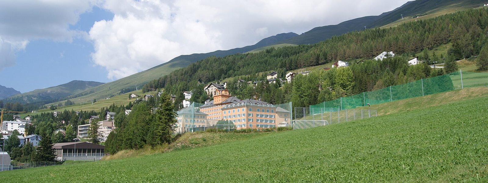 Le Lyceum Alpinum de Zuoz, grand bâtiment ocre au pied des pentes boisées de la Haute-Engadine